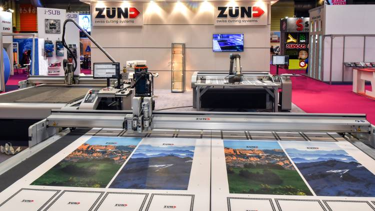 Featuring the clean red, black and white branding of Zünd, stand K30 attracted attention for its next-generation cutting systems, in particular a Zünd S3 L1200 fitted with a robotic arm.