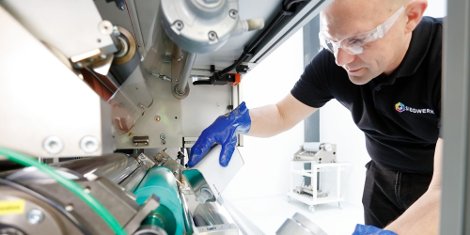 An employee of Siegwerk is preparing the lamination machine for a test lamination